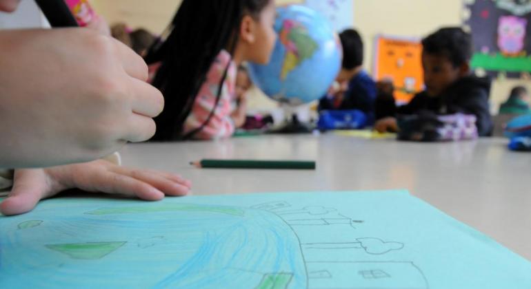 Crianças em uma sala de aula fazem desenho em cartolina