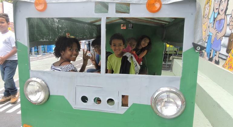 A E. M. Dom Orione, na região da Pampulha, criou a mini cidade “Belo Horione” para trabalhar comquestões de educação ambiental e cidadania. Foto: Divulgação PBH Duas crianças na traseira no ônibus de papelão.