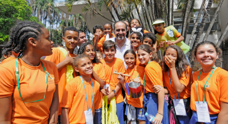 Mais de três mil estudantes se deslocaram em grupos, formando um grande cortejo que marcou a abertura oficial da Semana da Educação 2019. Foto: Amira Hissa/PBH Prefeito Alexandre Kalil cencado de mais de quize estudantes com camiseta laranja, ao lado do Teatro Francisco Nunes, durante o dia.