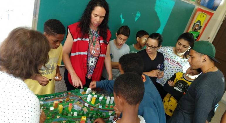 Intrutora mostra maquete para sete garotos da Rede de Ensino Fundamental.