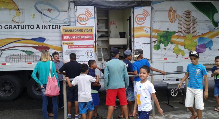 Foto mostra a Carreta do programa e algumas crianças na frente dela