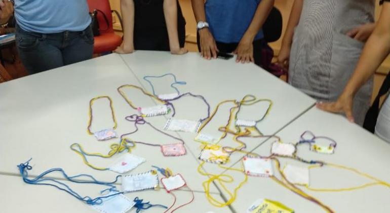 Integrarte Pessoas em volta de uma mesa olham para algumas peças de bijuterias