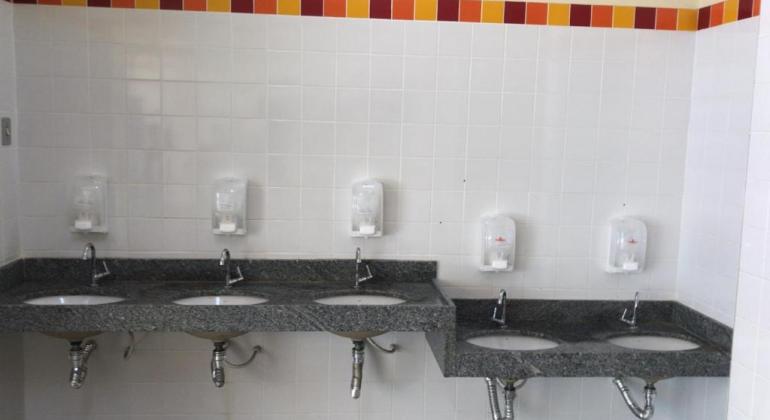 Banheiro de escola com dispenser de álcool em gel