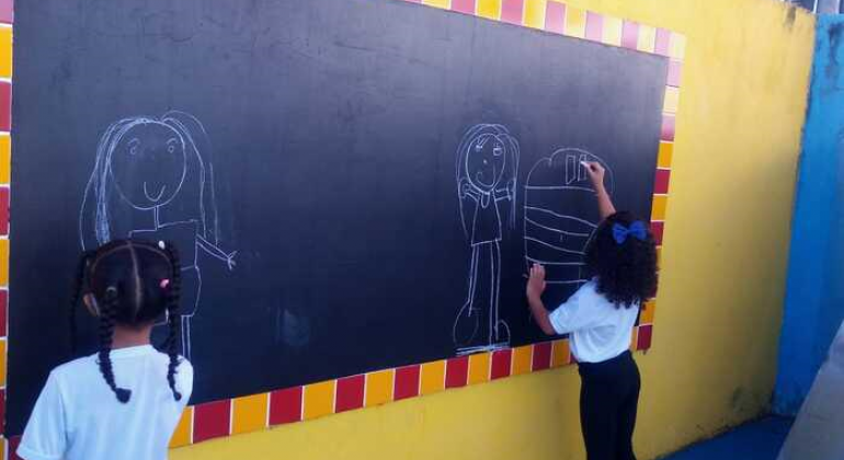 Duas crianças desenhando no quadro-negro