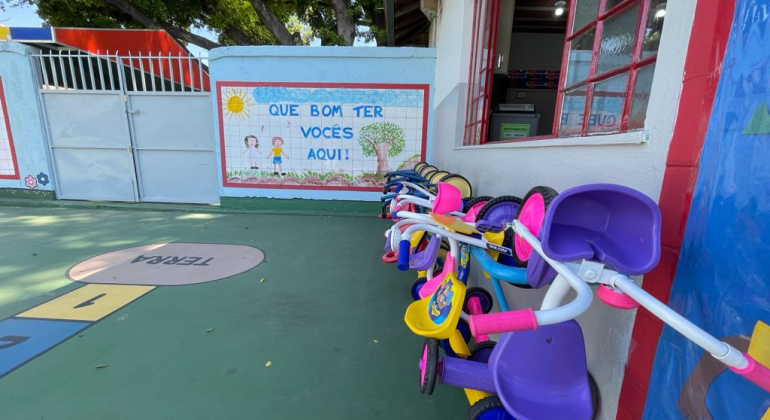 Pátio de escola com triciclos pendurados 