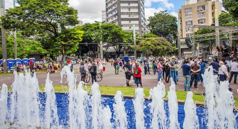 Pessoas passeiam no cruzamento das avenidas Getúlio Vargas com Cristóvão Colombo ao fundo; à frente, fonte da Savassi. 