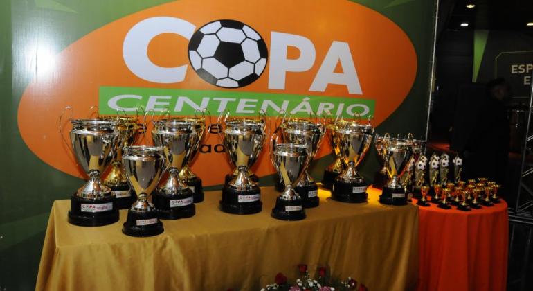 Troféus da Copa Centenário em cima de uma mesa. 