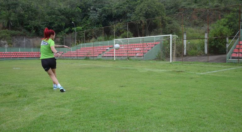 Semifinal feminina marca o domingo na Copa Centenário de Futebol Amador jogadora de futebol feminino chuta bola em direção ao gol no campo.
