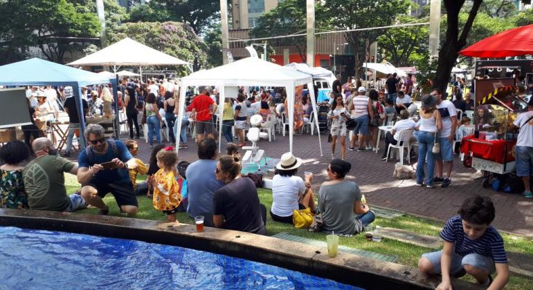 Pessoas se reúnem em uma praça com barracas de comidas e bebidas