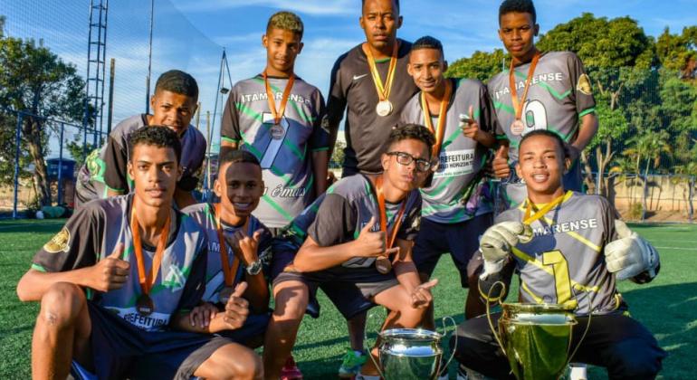 Meninos de um time de futebol mostram medalhas e troféu