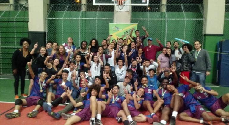 Grupo de jovens atletas posam para foto em quadra de esporte