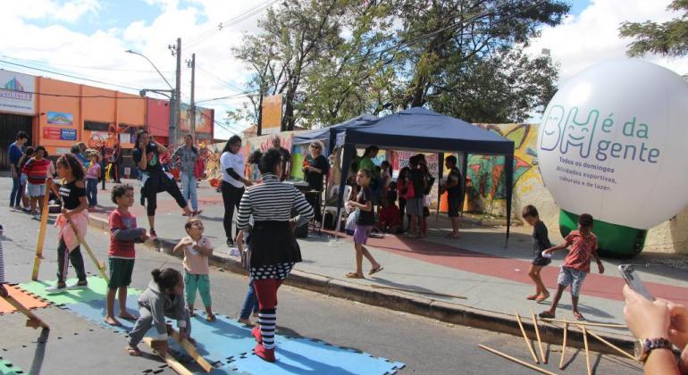 A ativação desse espaço reforçou o compromisso da PBH com a política pública de promover proteção social em uma área de vulnerabilidade. Foto: Stênio Lima/PBH Mais de cinco crianças brncam na rua, uma tenda está armada ao fundo, e à direita, o balão do BH é da Gente.