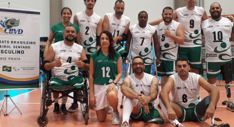 Dez integrantes da equipe SADA de vôlei sentado posam para foto. 