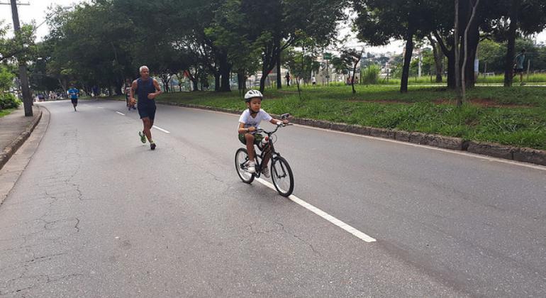 Criança andando de bicicleta na avenida
