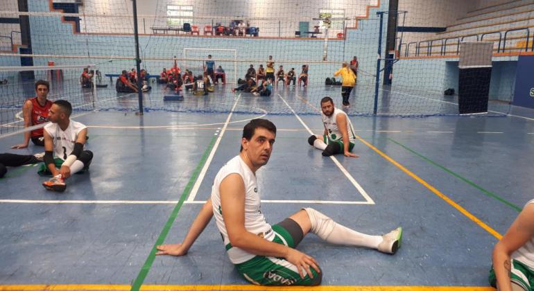 Em uma ponta da quadra preparada para o jogo de vôlei sentado, Gabriel posa para foto. 