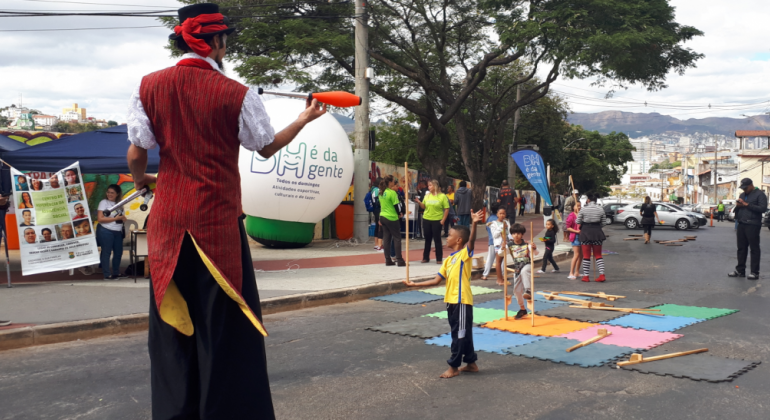 Atividades na área e saúde, oficina de técnicas circenses e atividades de recreação infantil fazem parte da programação do BH é da Gente. Foto: Vilma Tomaz/PBH Homem com perna de pau se apresenta para crianças, ao fundo, bola com os dizeres BH é da Gente.