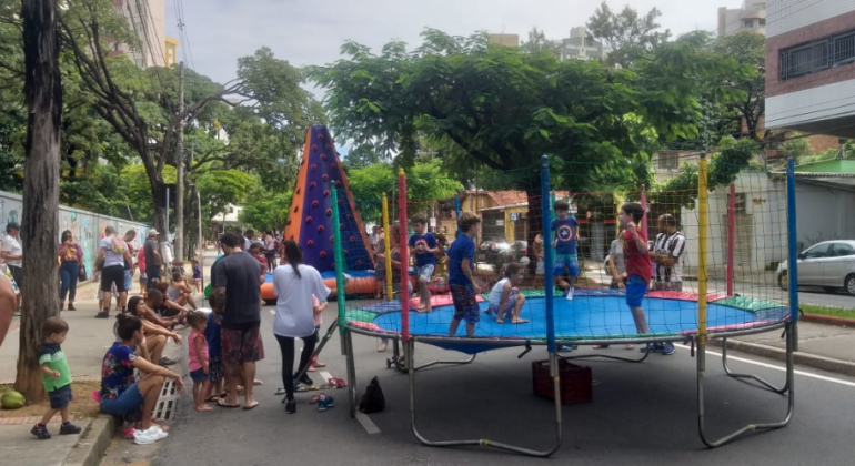 Ações recreativas e de saúde, com informações sobre a AIDS e outras infecções sexualmente transmissíveis, serão realizadas na rua Araribá. Foto: Daniela Magalhães Três crianças brincam no pula-pula enquanto adulto e mais duas crianças observam do lado de fora.