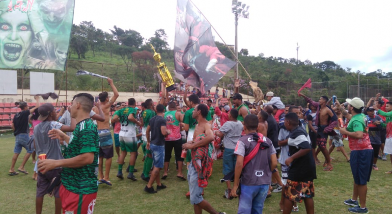 Time festeja título com a torcida. Há bandeiras e um troféu levantado