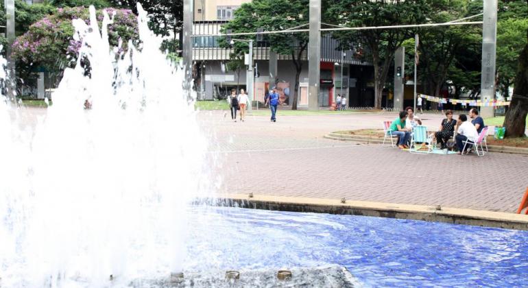 Praça da Savassi fechada com pessoas sentadas e uma fonte de água ligada