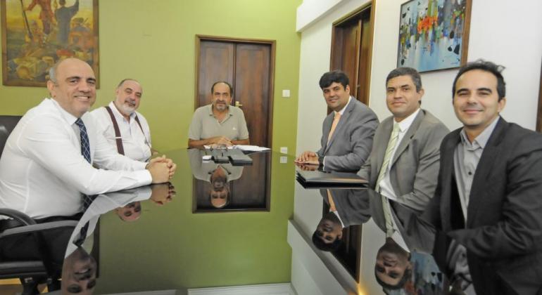 A PBH contratou uma operação de crédito junto ao Banco do Brasil no valor de R$ 180 milhões para obras de recapeamento de vias públicas. Foto: Amira Hissa/PBH O prefeito Alexandre Kalil e o secretário municipal da Fazenda, Fuad Noman, sentados à mesa, acompanhados de outros quatro membros da equipe.