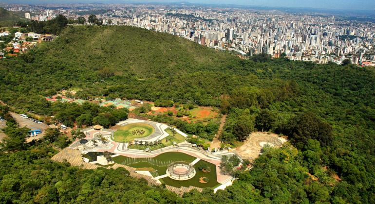 Foto aérea do Parque das Mangabeiras durante o dia. Ao fundo, área verde seguida de prédios da cidade de BH. 