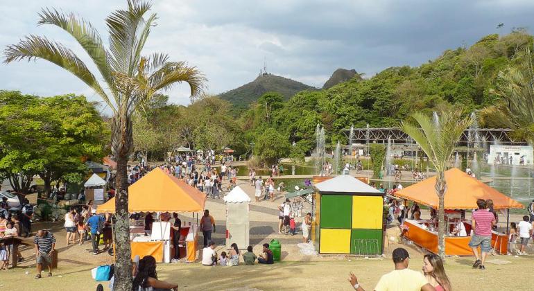 Parque das águas durante comemoração de dia das crianças. Há pessoas sentadas na grama e barracas montadas.