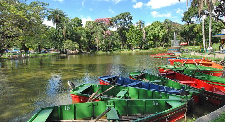 Lago do Parque Municipal Américo Renné Giannetti com barquinhos estacionados e muitas árvores no fundo.