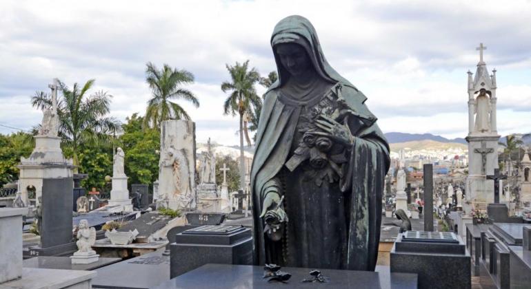 Domingo é dia de início do Projeto “Visitas Guiadas ao Cemitério do Bonfim”, que permite conhecer a riqueza arquitetônica do cemitério. Foto: Amira Hissa/PBH Estátua de Nossa Senhora em lápide do Cemitério do Bomfim; ao fundo, mais lápides.