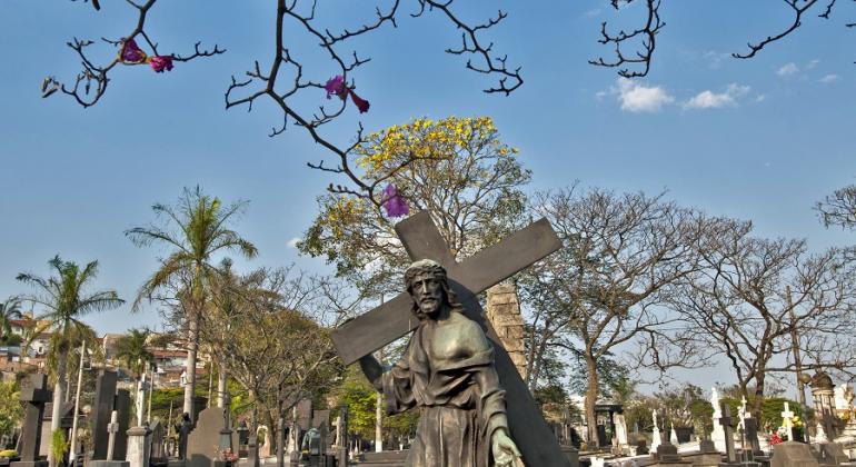 Quem for visitar os cemitérios municipais no dia 2/11 poderá consultar plantão administrativo para jazigos das 7h30 às 17h30. Foto: Vander Brás/PBH Foto de destátua de Jesus Cristo carregando a cruz em meio a outros túmulos com estátuas, durante o dia.
