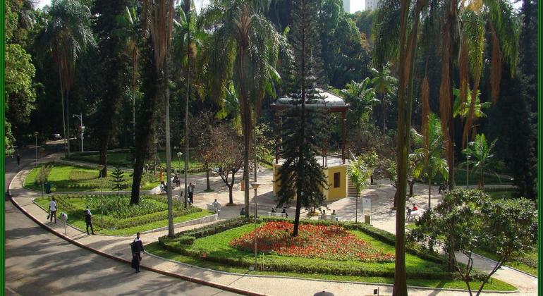 Confira os principais eventos gratuitos que acontecem em BH neste fim de semana, nos dias 30 e 31/3. Foto: Divulgação PBH Vista aérea do Parque Municipal, com cidade ao fundo e coreto e lago, durante o dia.