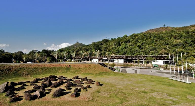 Parque das Mangabeiras, com pedras decorativas à frentes, ampla construção de um andar e vários ambientes, alguns abertos, ao meio, e parte da Serra do Curral, atrás. 