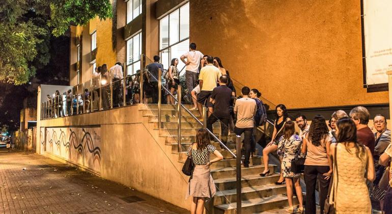 Mais de quarenta pessoas em fila do Teatro Marília, à noite