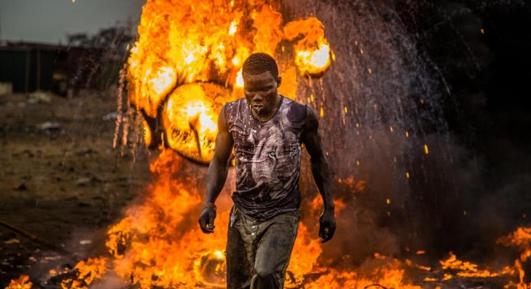 Homem caminha à frente de labaredas de fogo. Imagem do filme "Bem vindo à Sodoma". 