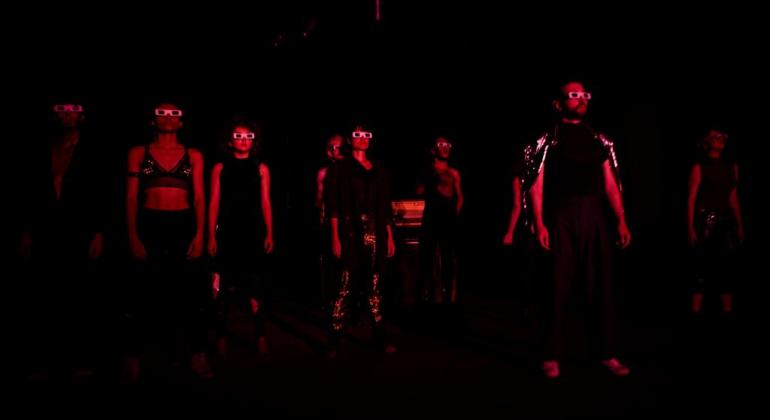 O espetáculo “Eclipse Solar” propõe uma experiência de teatro marcada pelo cinema e pela música, explorando as potências do audiovisual. Atores sob o palco, com pouca iluminação, usando óculos escuros