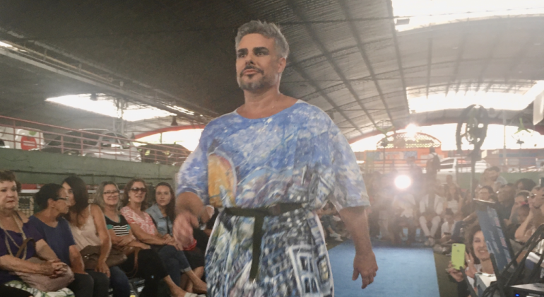 A Moda e a Cidade foi o tema da ação que aconteceu no Mercado Central, no sábado, dia 23/11, para encerrar o Mood - Festival de Moda de BH. Foto: Divulgação PBH Homem com bata colorida desfila no Mercado Central.