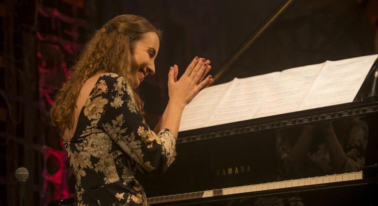 Mulher sentada tocando piano. 