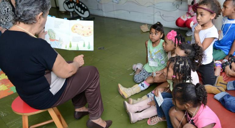 Prefeitura oferece programação cultural gratuita durante as férias escolares Crianças escutam histórias contadas por uma senhora