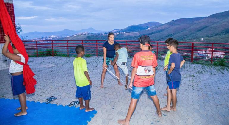 Sete crianças e uma monitora participando de brincadeiras com corda