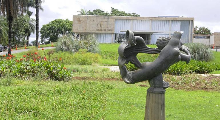Fachada do Museu de Arte da Pampulha, com escultura do jardim à frente, durante o dia.