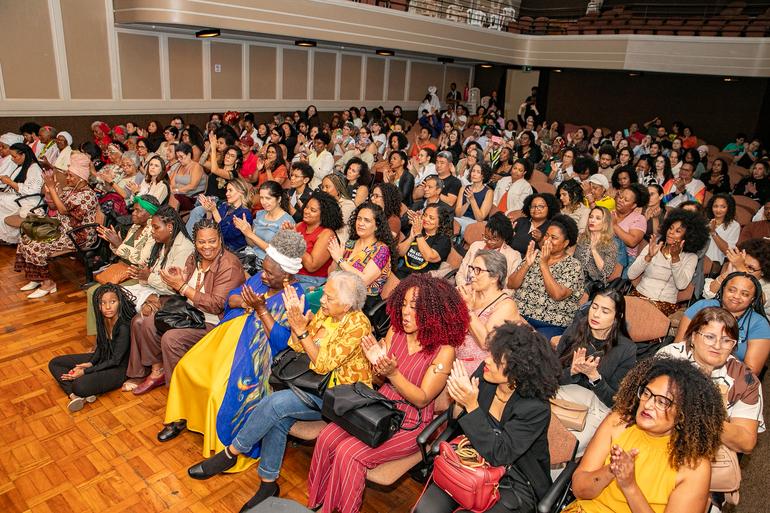 Multidão sentada em auditório aplaudindo 