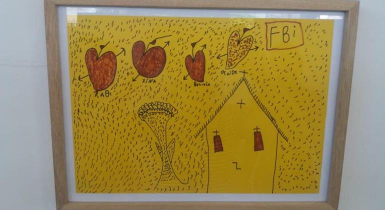 Exposição “A Viagem Nossa de Cada Dia” mostra os trabalhos dos usuários do Centro de Convivência Arthur Bispo, na região Leste. Foto: Divulgação PBH Quadro amarelo com igreja e corações.