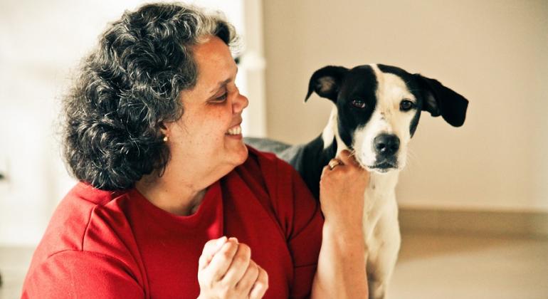 Evento tem o objetivo de abordar a importância da saúde animal para o meio ambiente e para as pessoas. Foto: Marina Jorda Mulher sorri para cão.