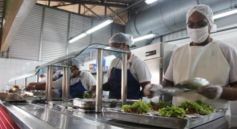 Prefeitura realiza tradicional Almoço de Natal nos Restaurantes Populares Mulher preparando almoço