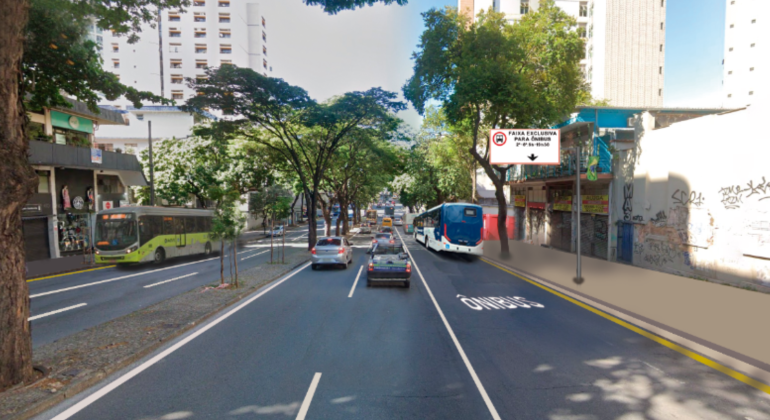 Fotografia de uma via urbana com três faixas de tráfego, árvores no canteiro central e prédios ao fundo. Na faixa da direita, há a pintura no asfalto indicando “ÔNIBUS” e uma placa aérea com os dizeres “Faixa exclusiva para ônibus – 2ª a 6ª, 6h às 9h e 16h às 20h”. Alguns veículos circulam na via, incluindo ônibus e carros.