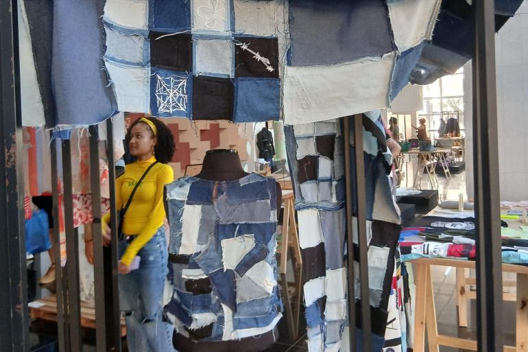 Encontro na PBH debate estratégias de economia circular na cadeia produtiva da moda Espaço expositivo com estrutura interativa em patchwork de jeans reutilizado, unindo bordados expressivos, texturas e design autoral em uma experiência imersiva de moda sustentável.
