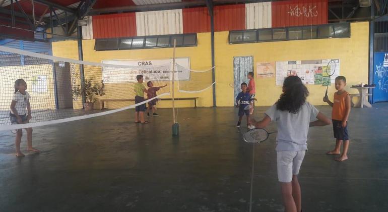 Três crianças de um lado da quadra, jogando badminton.