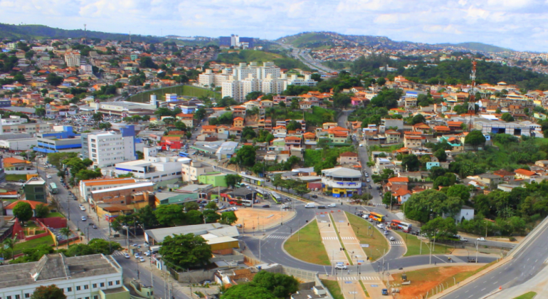 Vista aérea da região do Vilarinho, com prédios, casas e rotatória. 