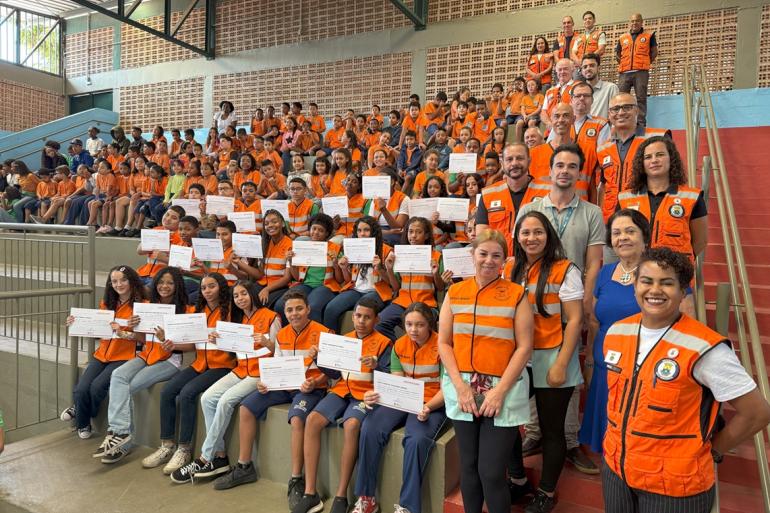 Defesa Civil nas Escolas crianças posam para foto com coleta da Defesa Civil e cetificados nas mãos