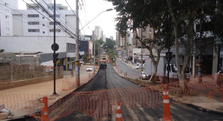 Rua com recapeamento sendo realizado e cones de proteção à frente.