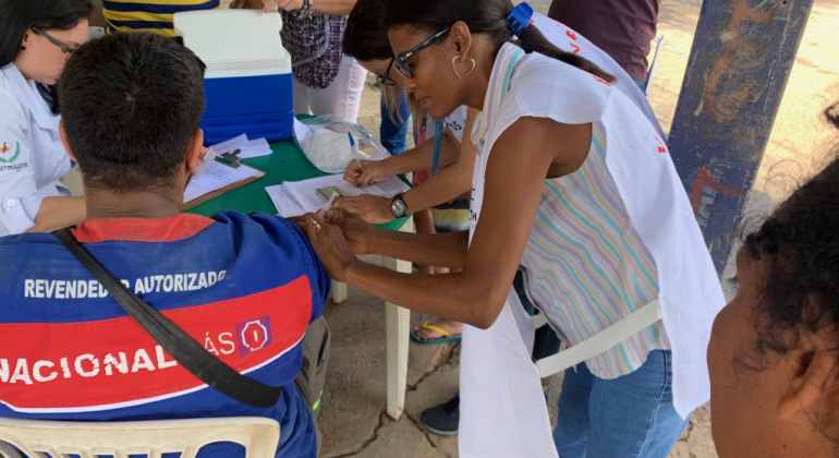 Funcionária da saúde aplicando a vacina em um morador da região Oeste.